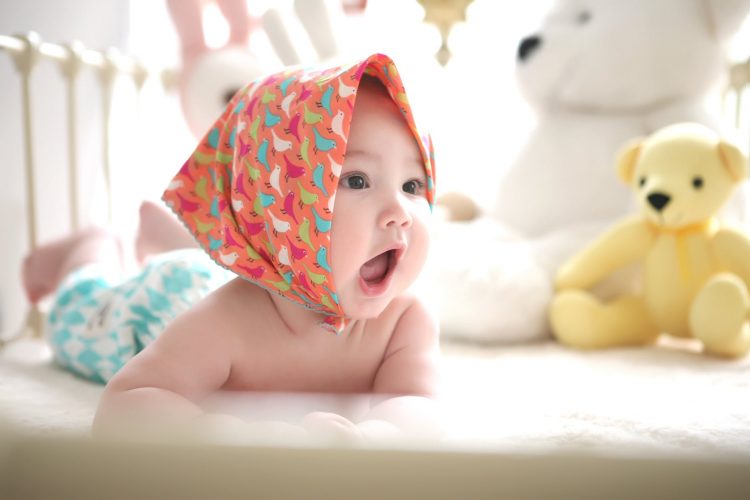niemowlak w łóżeczku z kolorową chusteczką na główce