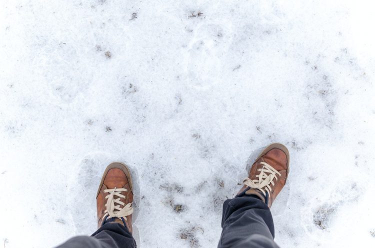 Mężczyzna w zimowych butach stoi na śniegu