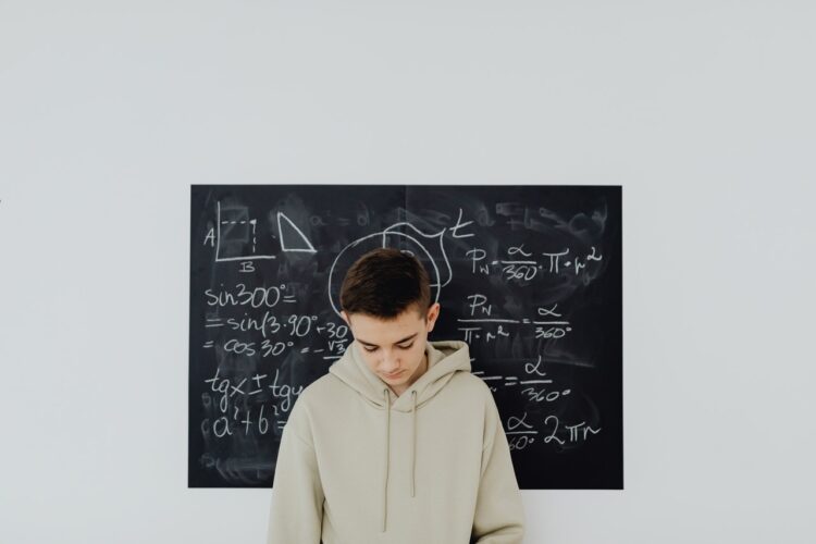Chłopak trzyma w dłoniach książke do matematyki i uczy się do matury