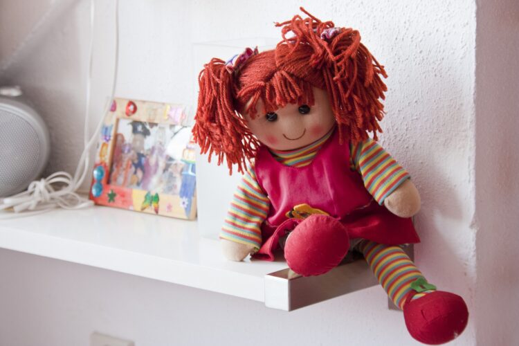 Materiałowa lalka leży na półce w pokoju dziecka
