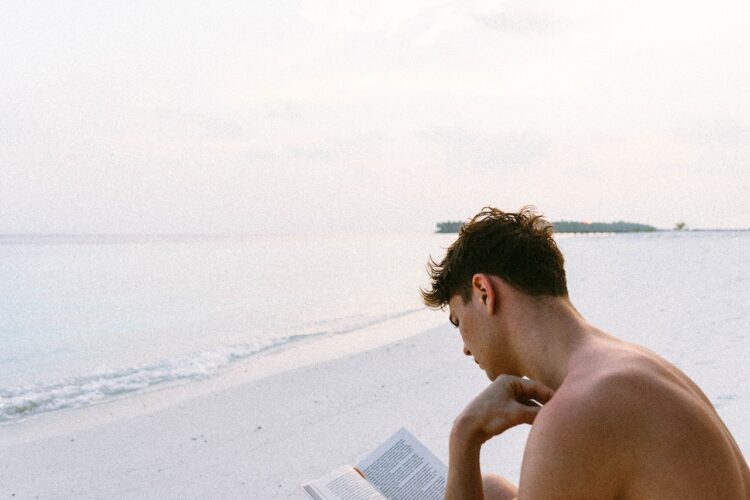 Mężczyzna czyta książkę psychologiczną nad morzem
